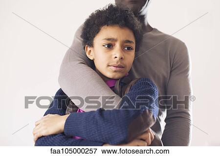 Stock Photo - Boy leaning against father with worried expression on face. Fotosearch