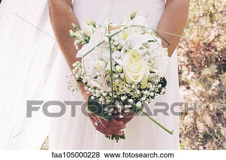 Stock Photo - Bride holding bouquet of flowers, cropped. Fotosearch