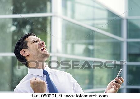 Businessman holding cell phone and celebrating good news View Large Photo Image Stock Photo - Businessman holding cell phone and celebrating good news. Fotosearch
