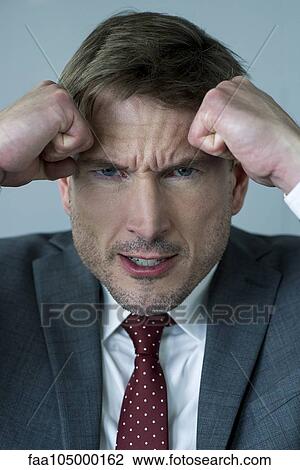 Businessman holding clenched fists against head in anger, portrait View Large Photo Image Stock Image - Businessman holding clenched fists against head in anger, portrait. Fotosearch