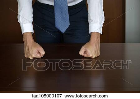 Stock Photo - Businessman pounding fists on table, cropped. Fotosearch