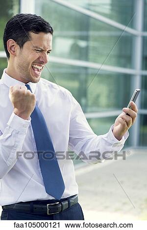 Stock Image - Businessman receiving good news via cell phone. Fotosearch