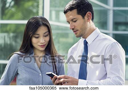 Businessman showing smartphone to colleague View Large Photo Image Stock Photography - Businessman showing smartphone to colleague. Fotosearch