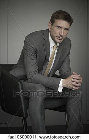 Stock Image - Businessman sitting in chair, portrait. Fotosearch