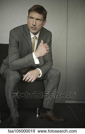 Stock Photo - Businessman sitting in waiting room chair with worried expression on face. Fotosearch
