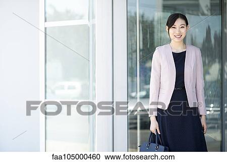 Businesswoman standing in front of office building, smiling, portrait View Large Photo Image Stock Image - Businesswoman standing in front of office building, smiling, portrait. Fotosearch