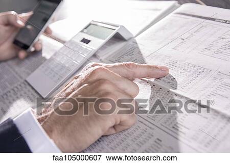 Checking stock market performance in newspaper View Large Photo Image Stock Photo - Checking stock market performance in newspaper. Fotosearch