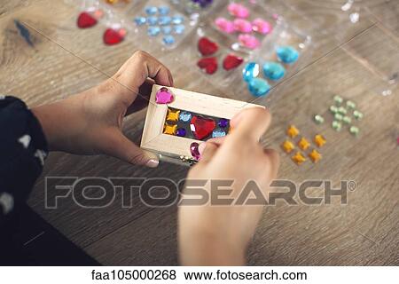 Child decorating box with stick-on jewels, cropped View Large Photo Image Stock Photo - Child decorating box with stick-on jewels, cropped. Fotosearch