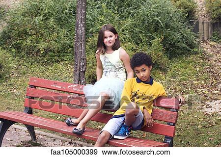 Children sitting together on park bench View Large Photo Image Stock Photo - Children sitting together on park bench. Fotosearch