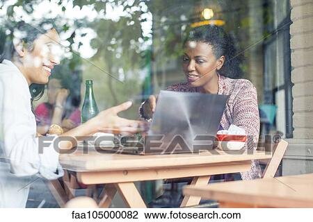 Stock Image - Colleagues discussing work in coffee shop. Fotosearch