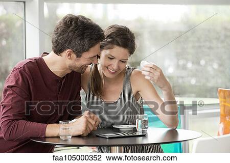 Couple in cafe watching video streaming on digital tablet View Large Photo Image Stock Image - Couple in cafe watching video streaming on digital tablet. Fotosearch