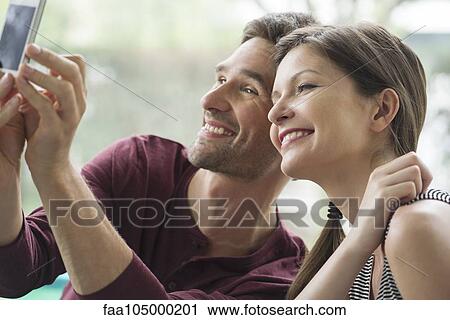 Stock Image - Couple posing for a selfie with a smartphone. Fotosearch