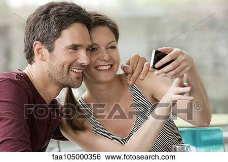 Couple posing for smartphone selfie View Large Photo Image Stock Photograph - Couple posing for smartphone selfie. Fotosearch