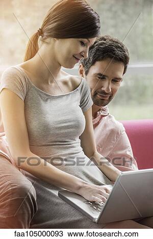 Couple relaxing together on sofa with laptop computer View Large Photo Image Stock Image - Couple relaxing together on sofa with laptop computer. Fotosearch