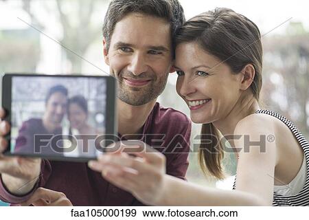 Couple using digital tablet to take a selfie View Large Photo Image Stock Photo - Couple using digital tablet to take a selfie. Fotosearch