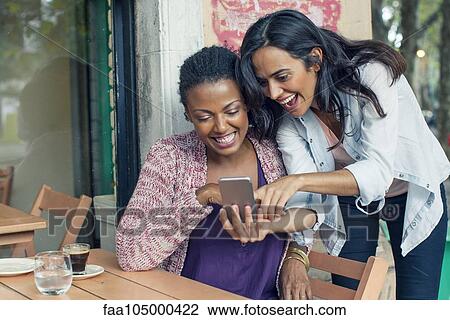 Friends looking at smartphone together View Large Photo Image Stock Image - Friends looking at smartphone together. Fotosearch