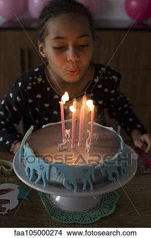 Picture - Girl blowing out candles on birthday cake. Fotosearch