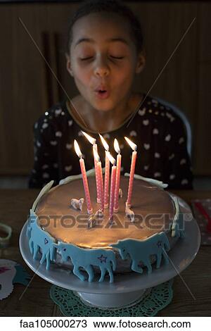 Stock Image - Girl blowing out candles on birthday cake. Fotosearch