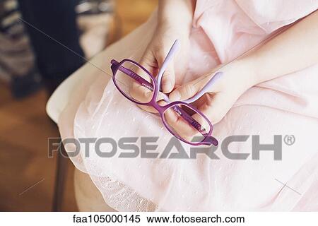 Girl holding pair of glasses on lap, cropped View Large Photo Image Stock Photography - Girl holding pair of glasses on lap, cropped. Fotosearch