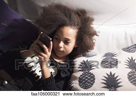 Girl lying down, using smartphone View Large Photo Image Stock Image - Girl lying down, using smartphone. Fotosearch