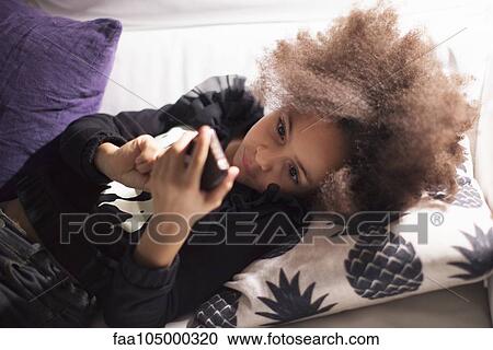 Girl lying on sofa using smartphone View Large Photo Image Stock Image - Girl lying on sofa using smartphone. Fotosearch