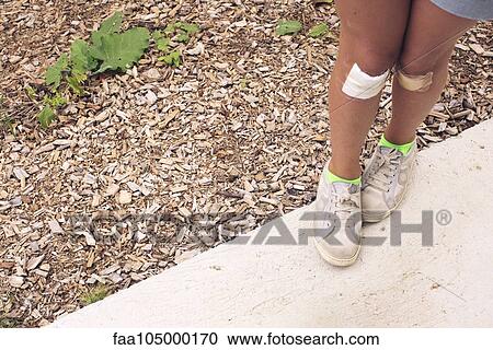 Stock Image - Girl with both knees bandaged, cropped. Fotosearch