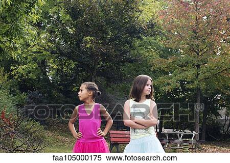 Girls standing together outdoors, both looking away angrily View Large Photo Image Stock Photography - Girls standing together outdoors, both looking away angrily. Fotosearch