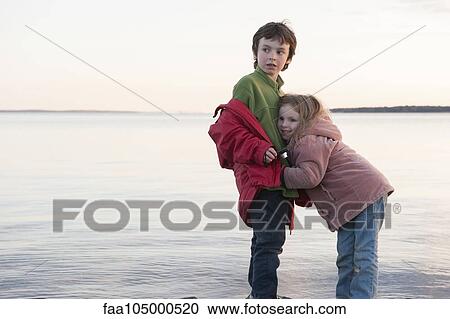 Stock Image - Little girl hugging her brother at water's edge. Fotosearch