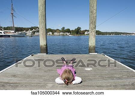 Little girl lying on dock with hands behind head View Large Photo Image Picture - Little girl lying on dock with hands behind head. Fotosearch