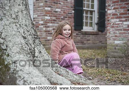 Little girl sitting at base of tree, smiling, portrait View Large Photo Image Stock Photo - Little girl sitting at base of tree, smiling, portrait. Fotosearch
