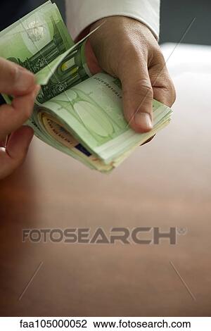 Stock Image - Man counting stack of money, cropped. Fotosearch