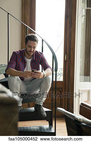 Man sitting on staircase using smartphone View Large Photo Image Stock Image - Man sitting on staircase using smartphone. Fotosearch