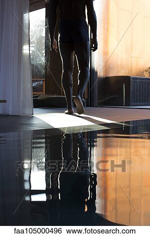 Stock Photograph - Man walking away from indoor pool, cropped. Fotosearch