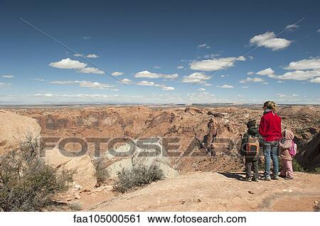 Stock Image - Mother and children standing at edge of canyon in Canyonlands National Park, Utah, USA. Fotosearch