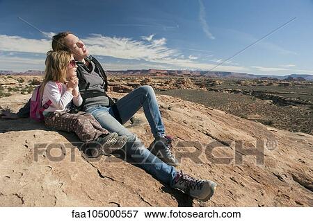 Stock Photo - Mother and daughter resting on rock in Canyonlands National Park, Utah, USA. Fotosearch
