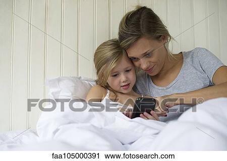 Mother and daughter using smartphone together View Large Photo Image Stock Image - Mother and daughter using smartphone together. Fotosearch