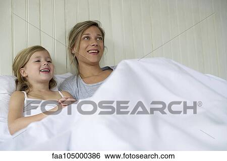 Mother and daughter watching tv together in bed View Large Photo Image Stock Photograph - Mother and daughter watching tv together in bed. Fotosearch