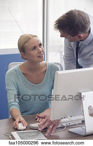 Stock Photograph - Office worker explaining process to new employee. Fotosearch