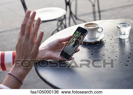 Stock Photograph - Person video chatting with a smartphone, cropped. Fotosearch