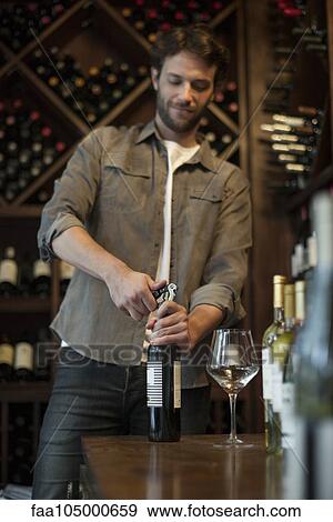 Stock Photo - Sommelier uncorking bottle of wine. Fotosearch