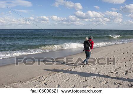 Vacationer walking on beach with small child on back during the off season View Large Photo Image Stock Image - Vacationer walking on beach with small child on back during the off season. Fotosearch