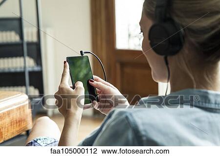 Stock Image - Woman browsing internet using smartphone. Fotosearch