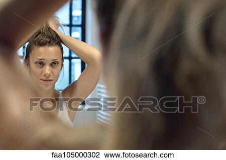 Woman doing hair in bathroom mirror View Large Photo Image Stock Image - Woman doing hair in bathroom mirror. Fotosearch