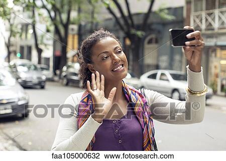 Stock Image - Woman doing video chat on street. Fotosearch
