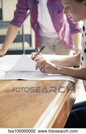 Woman explaining paperwork to colleague View Large Photo Image Stock Image - Woman explaining paperwork to colleague. Fotosearch
