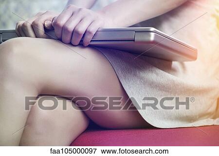 Stock Photo - Woman holding closed laptop computer on lap, cropped. Fotosearch