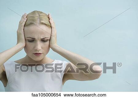 Picture - Woman holding hands over ears, looking down with furrowed brow. Fotosearch
