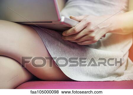 Stock Photo - Woman holding laptop computer on lap, cropped. Fotosearch