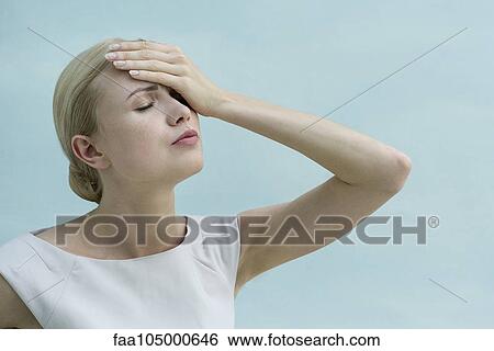 Stock Photograph - Woman holding one hand on forehead, eyes closed. Fotosearch