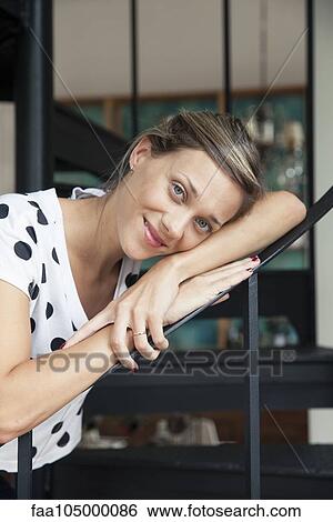Stock Photograph - Woman leaning against bannister, portrait. Fotosearch